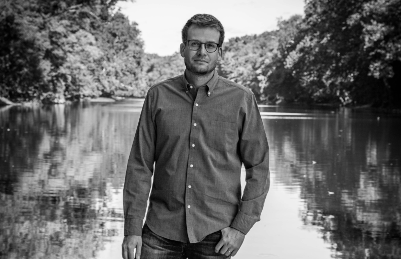 Black and white photo of John Green standing in nature 